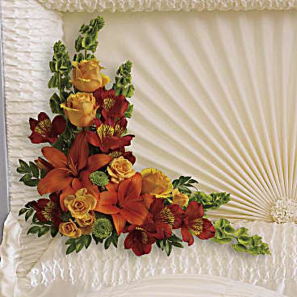 Casket spray with orange lilies, red flowers, and yellow roses