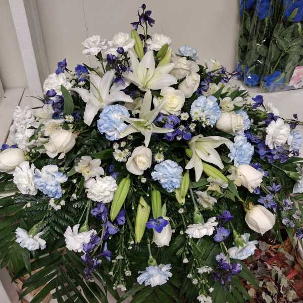 Large white and blue floral arrangement with lilies and roses