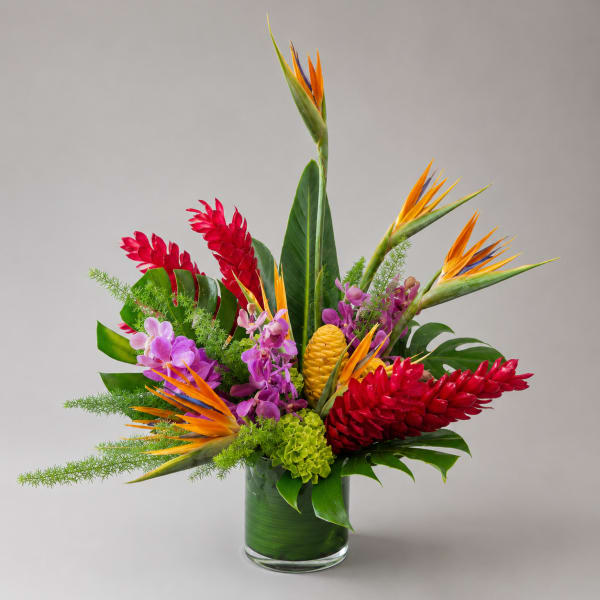 Tropical bouquet with red ginger, bird of paradise, orchids, and green foliage in a glass vase