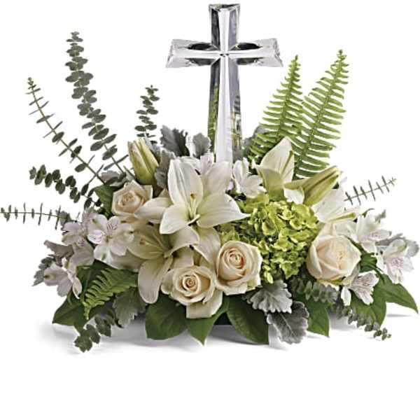 White lilies and roses arranged around a silver cross