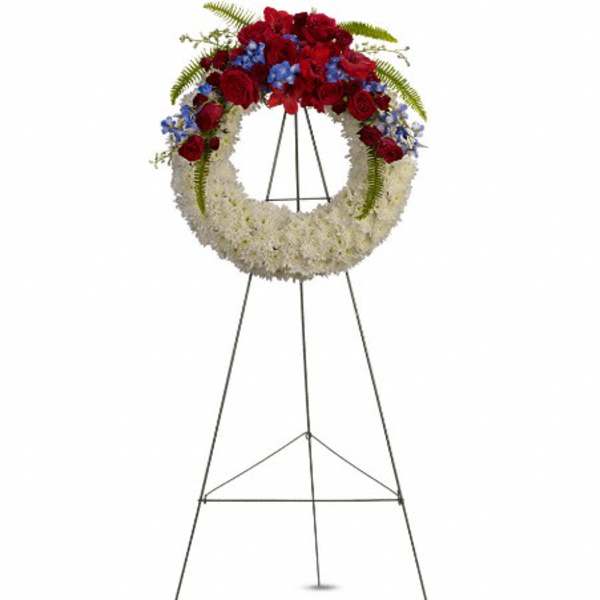 Standing floral wreath with red, white, and blue flowers on an easel