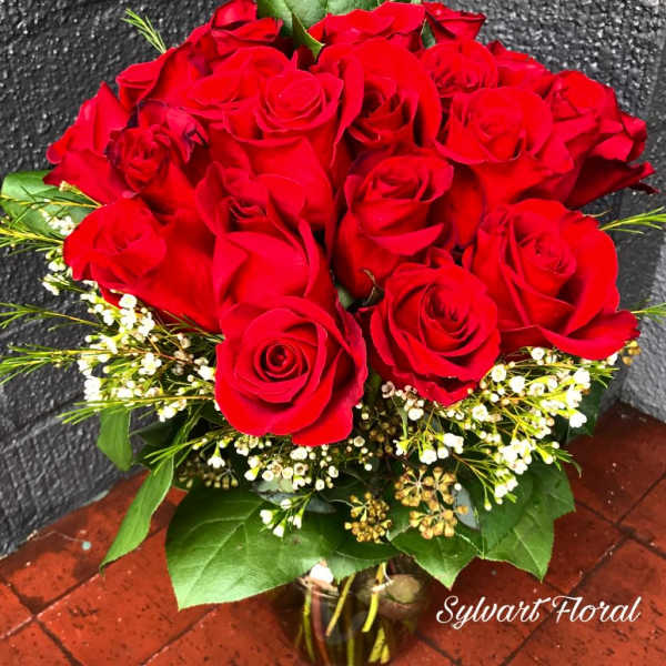 Bouquet of red roses with small white filler flowers in a glass vase