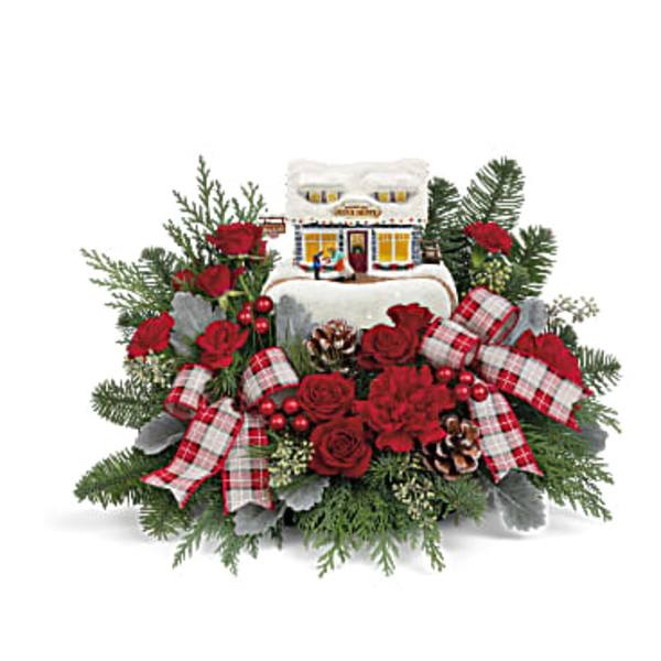 Christmas floral arrangement with red roses, plaid ribbons, and a small house ornament