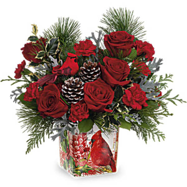 Red roses and carnations in a glass vase with pinecones and evergreen accents