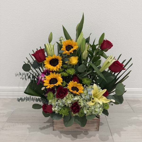 Mixed bouquet with sunflowers, red roses, and lilies in a wooden box