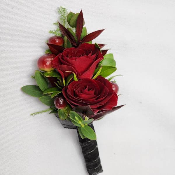 Red rose boutonniere with berries and greenery on a black wrapped stem