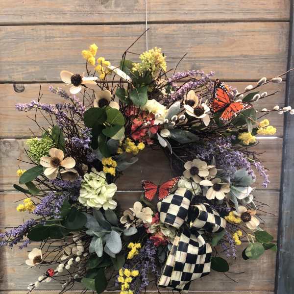 Floral wreath with cream flowers, purple accents, and a checkered bow