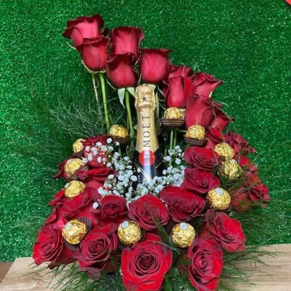 Red roses arranged around a champagne bottle with chocolates