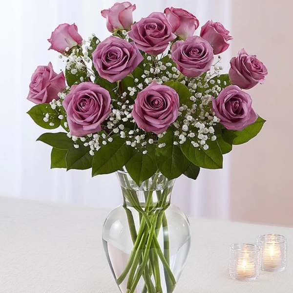 Arrangement of lavender roses with white baby's breath in a clear glass vase