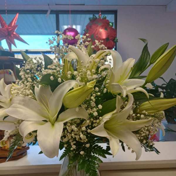White lilies and baby's breath in a clear glass vase