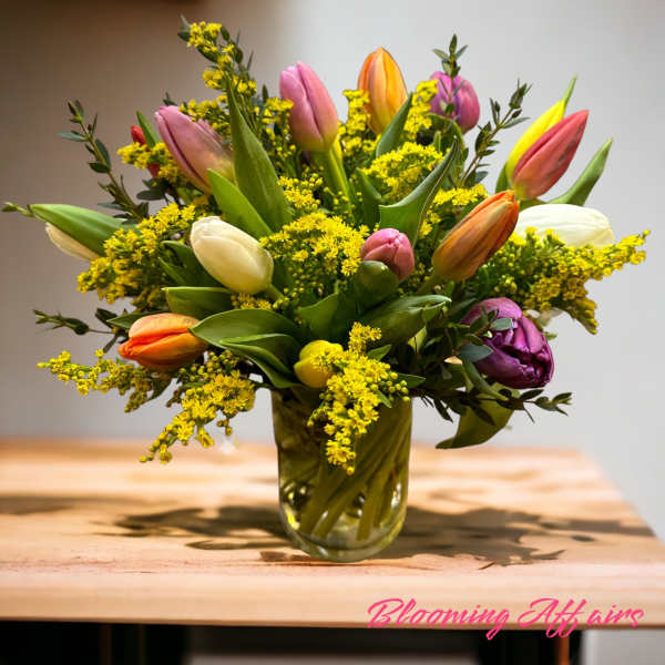 Mixed tulip bouquet in a glass vase with yellow filler flowers