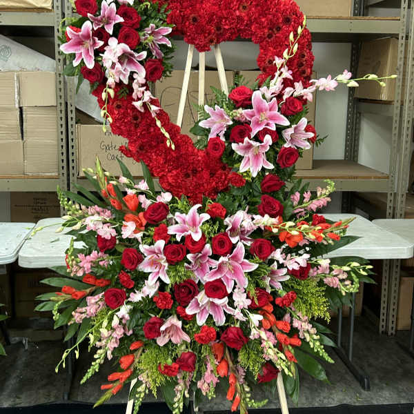 Large heart-shaped floral standing spray with red roses and pink lilies