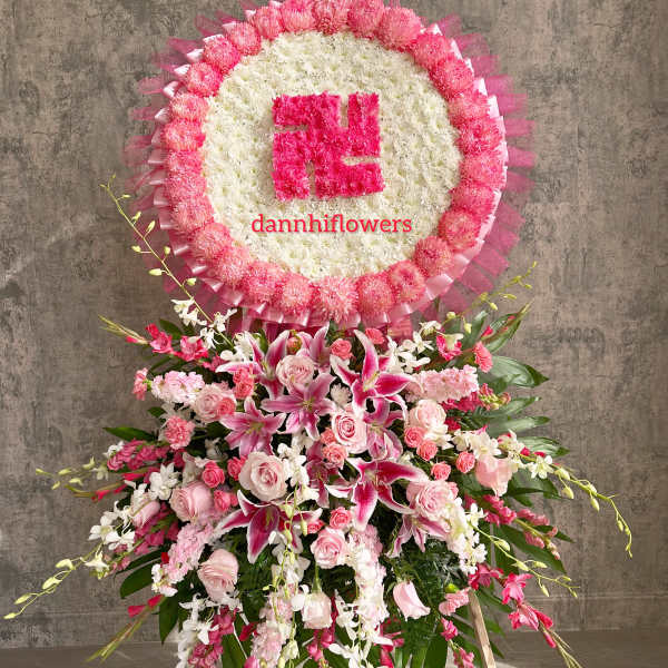 Pink and white funeral standing spray with a circular floral tribute above it
