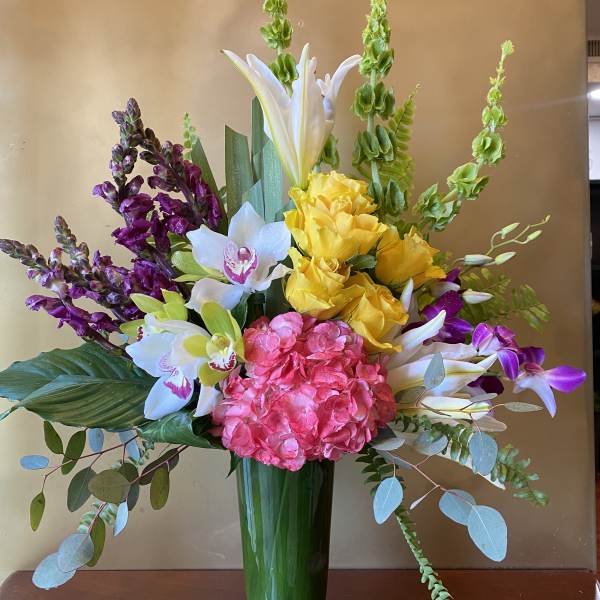 Mixed bouquet with hydrangea, orchids, roses, and lilies in a glass vase