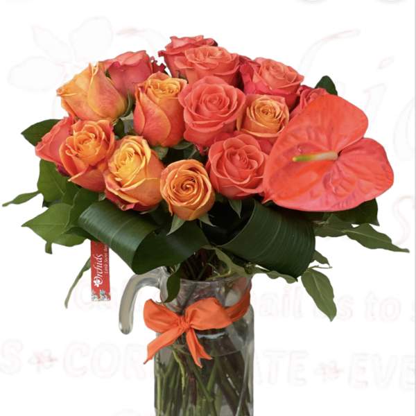 Bouquet of orange and coral roses in a glass pitcher vase