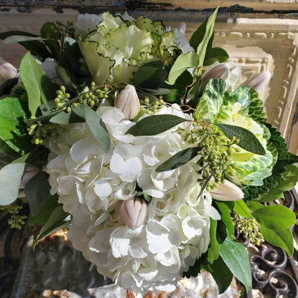 White hydrangea bouquet with pale pink tulips and green foliage