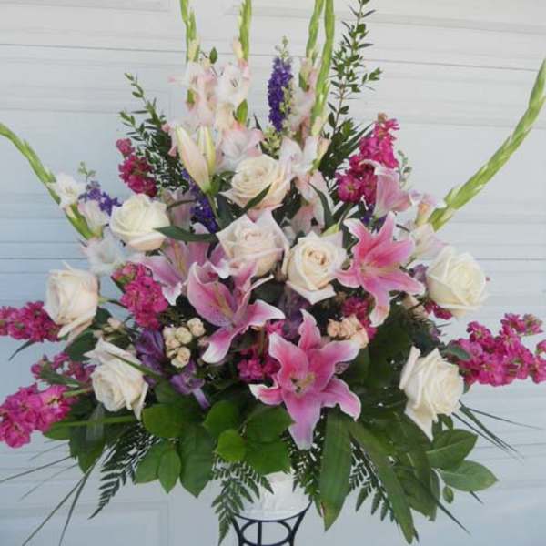 Tall floral arrangement with pink lilies, white roses, and purple accents