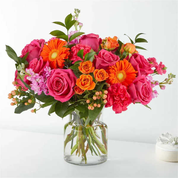 Pink and orange mixed flower bouquet in a clear glass vase