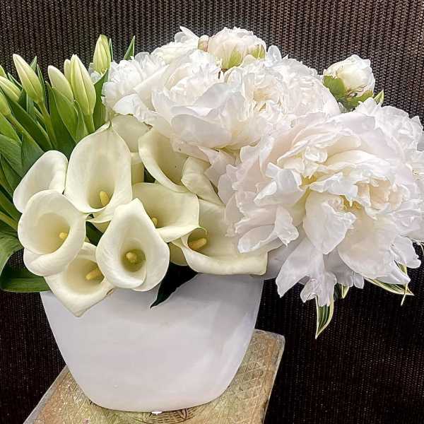 White calla lilies and peonies in a white vase