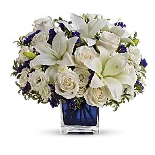 White lilies and roses arranged in a blue glass vase