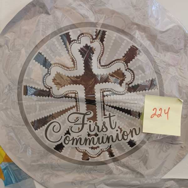 Round decorative plaque with a cross and the words First Communion
