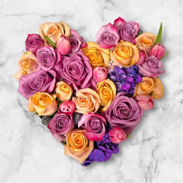 Heart-shaped bouquet of multicolored roses on a marble surface