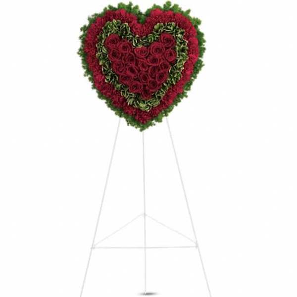 Heart-shaped standing floral tribute with red roses and greenery on an easel