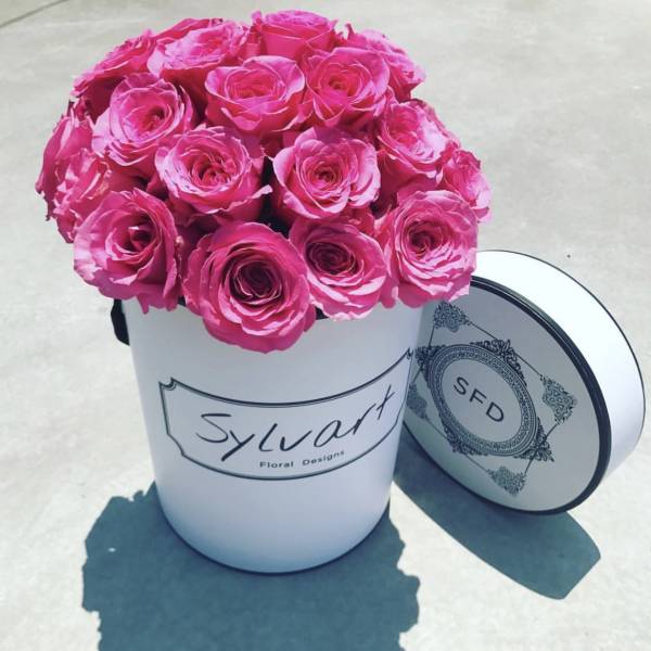 Hot pink roses arranged in a white hat box with a matching lid