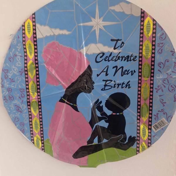 Round decorative sign with silhouettes and the words "To Celebrate A New Birth"