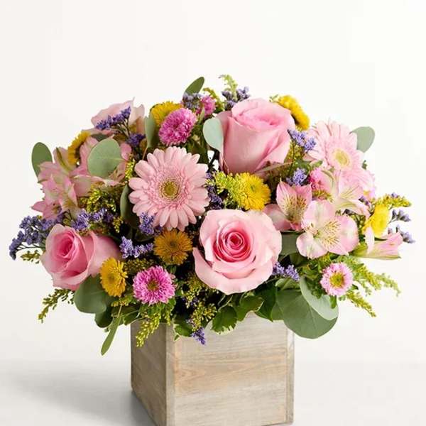 Pink roses and mixed flowers arranged in a wooden box