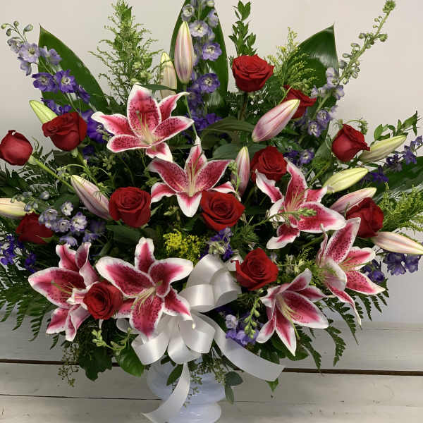 Large bouquet of pink lilies, red roses, and purple flowers in a white vase