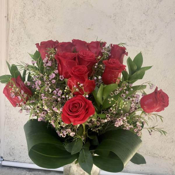 Bouquet of red roses with pink filler flowers in a clear glass vase