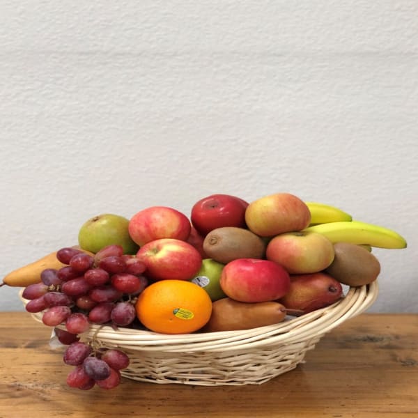 Basket of assorted fruit including grapes, bananas, apples, pears, and an orange