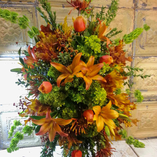 Tall autumn floral arrangement with orange lilies and green blooms