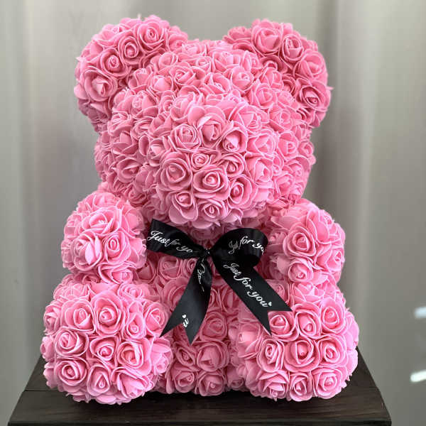 Pink teddy bear made of roses with a black ribbon