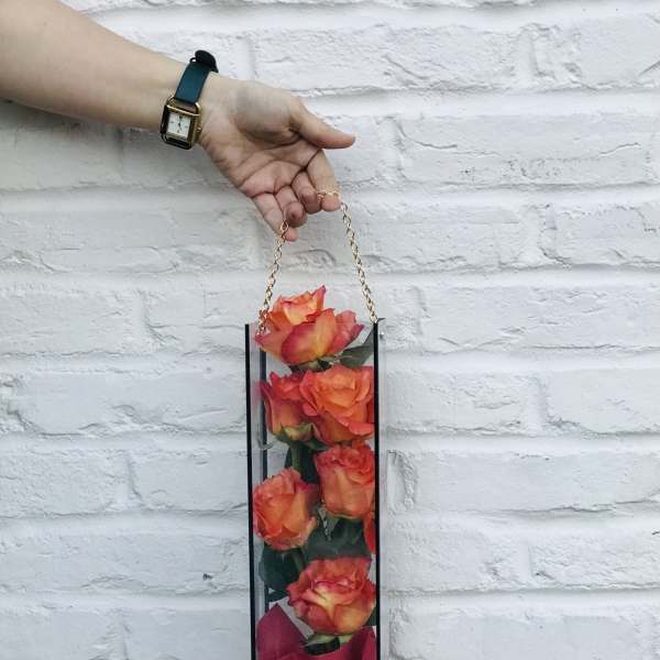 Tall box of orange roses with a pink wrap and chain handle