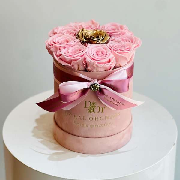 Pink roses arranged in a round hat box with a ribbon bow