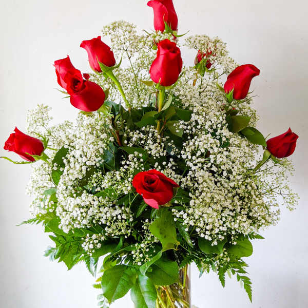 Red roses arranged with white baby's breath in a clear glass vase