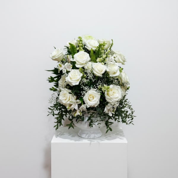 White rose arrangement in a clear pedestal vase