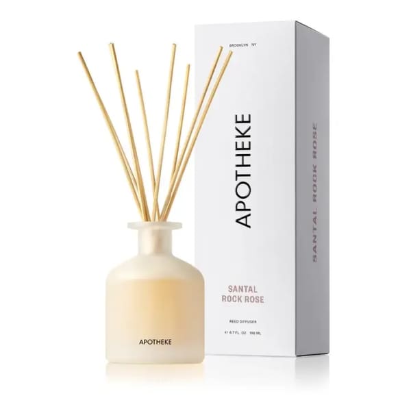 Cream glass reed diffuser with wooden sticks beside tall white Apotheke box