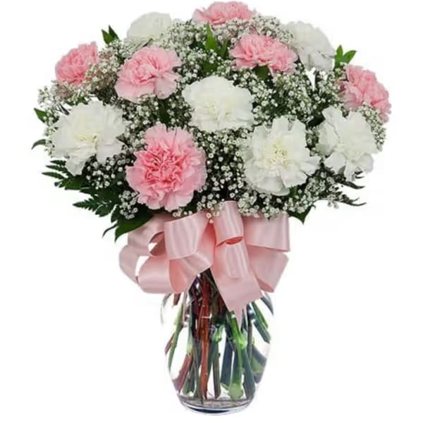 Pink and white carnations in a clear glass vase with a pink ribbon