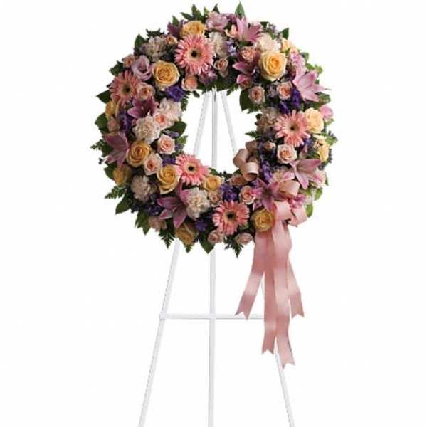 Floral wreath on a white stand with pink ribbon