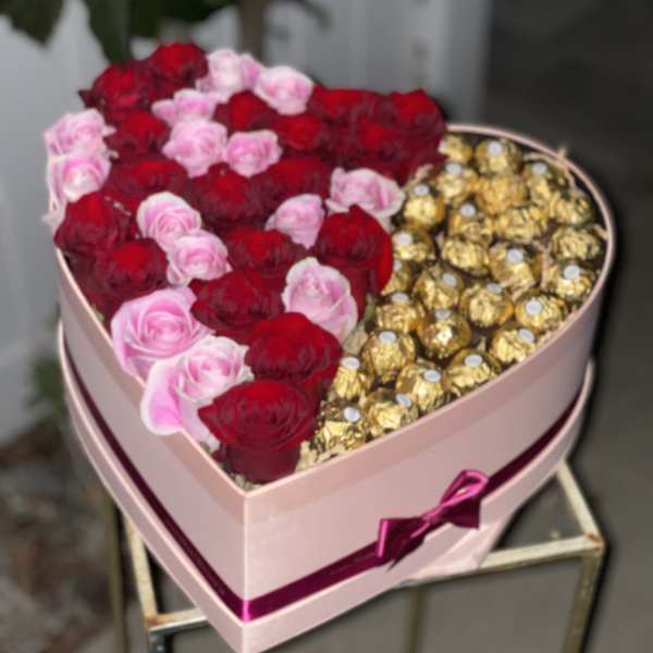 Heart-shaped box with red and pink roses and gold-wrapped chocolates