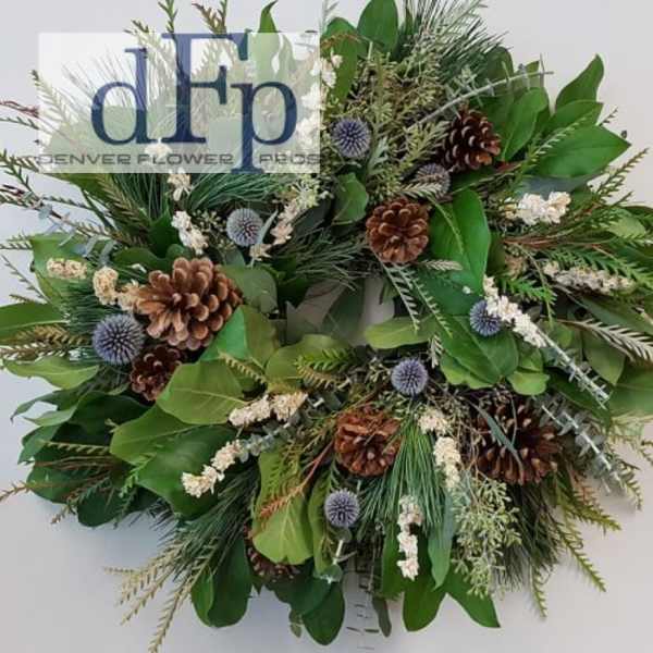 Green wreath with pinecones and small blue thistle-like accents