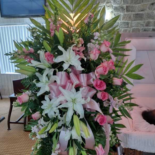 Large standing floral spray with pink roses and white lilies on an easel