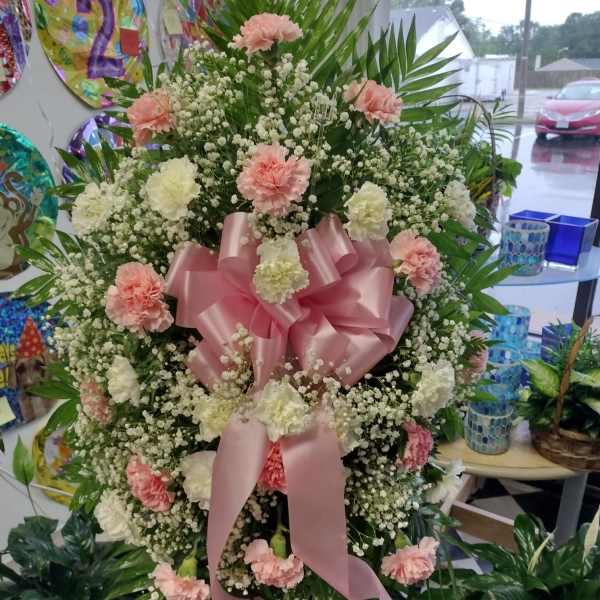 Large pink and white floral standing spray with a pink ribbon bow