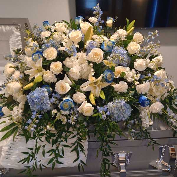 Large white and blue floral casket spray with roses and lilies
