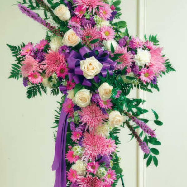 Standing floral cross with pink and white flowers and a purple ribbon