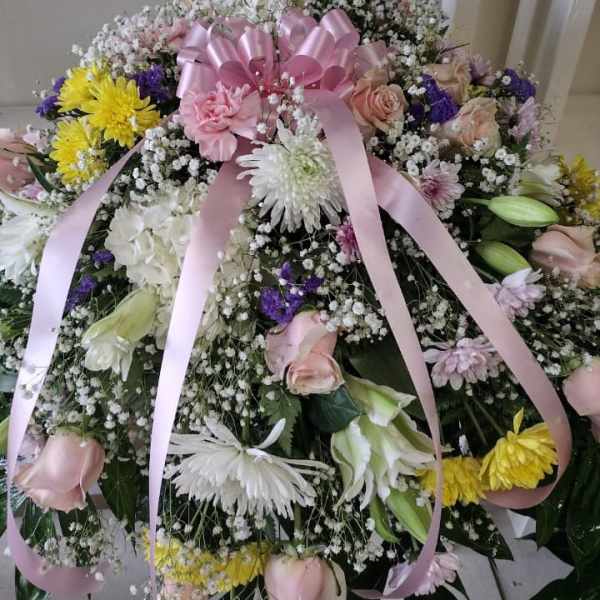 Large bouquet of pink roses, white lilies, and yellow chrysanthemums with a pink ribbon