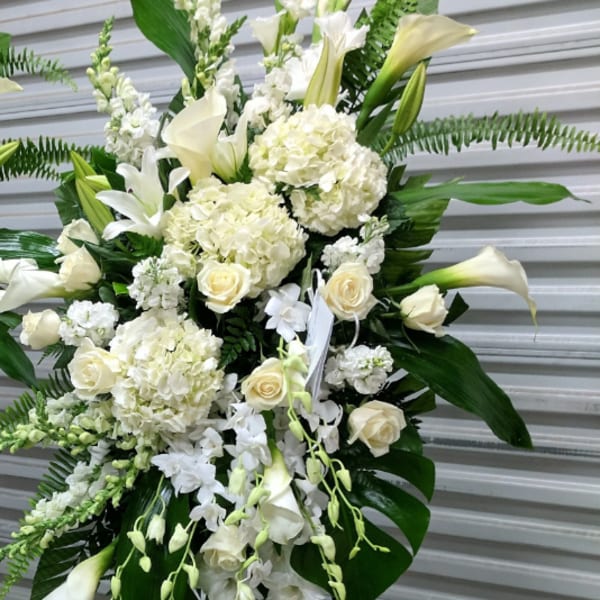 White floral standing spray with roses, lilies, and calla lilies